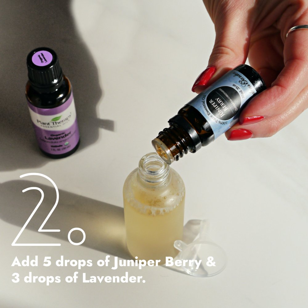 Hand dropping Juniper essential oil into glass bottle.