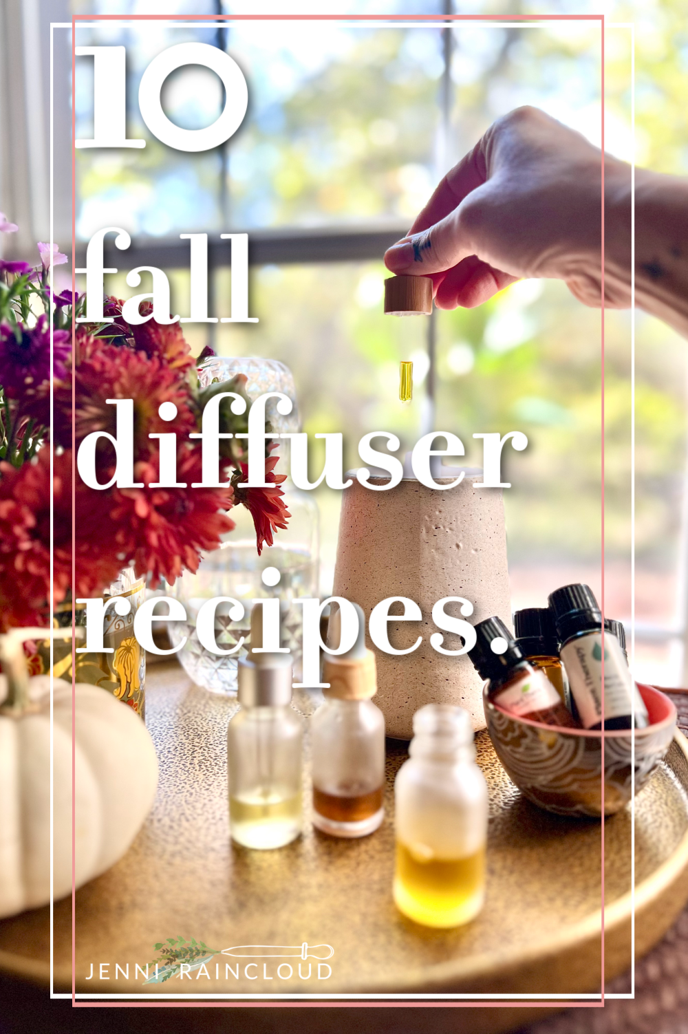 Hand adding essential oils to a diffuser w/ white pumpkin and mums