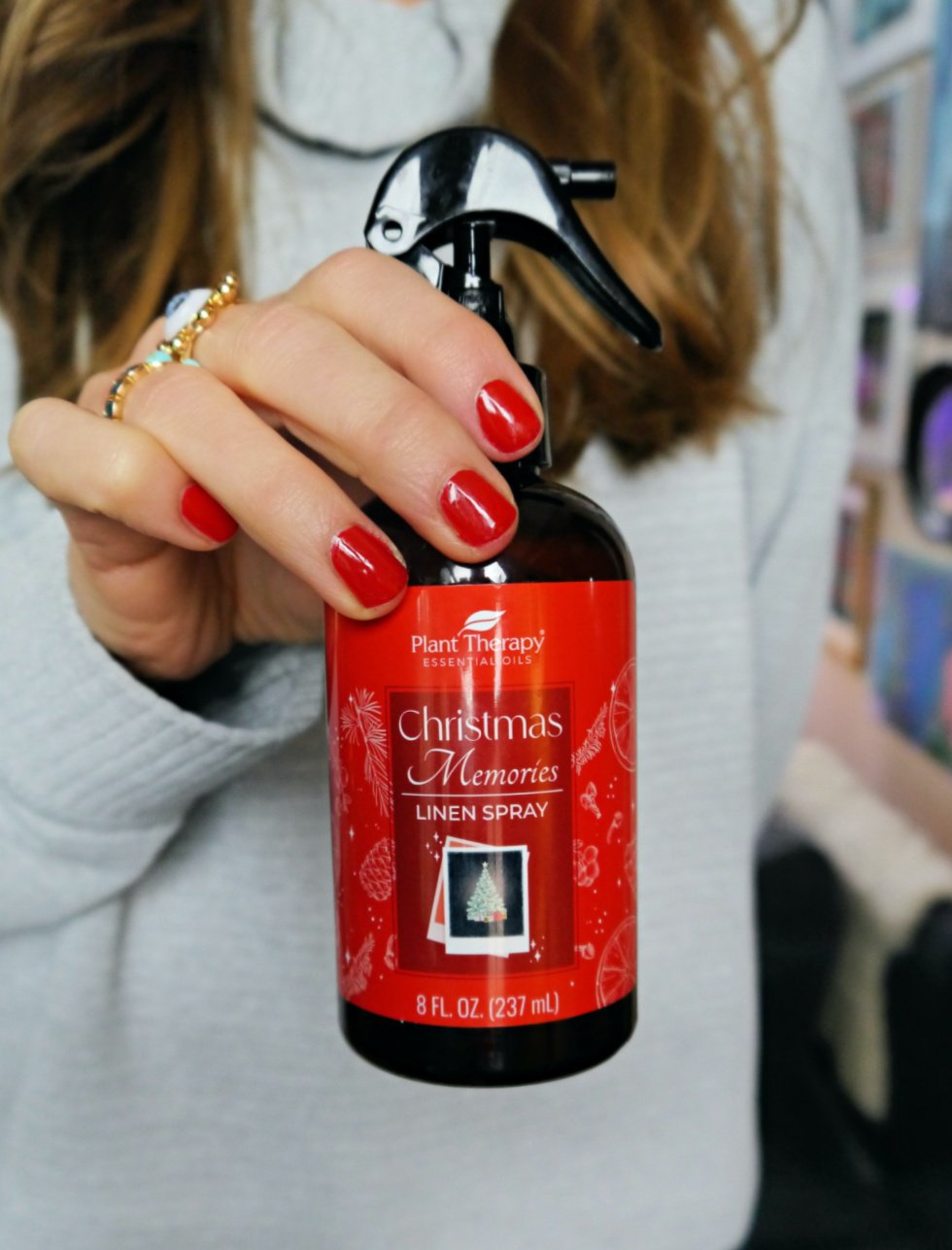 Hands with red nails holding Plant Therapy's Linen Spray